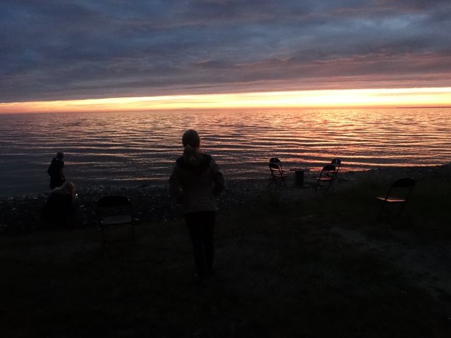 Folks on the shore enjoying the sunset.